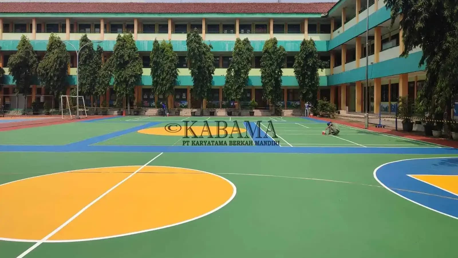 Lapangan olahraga serbaguna dengan cat hijau, biru, dan kuning yang baru selesai dikerjakan